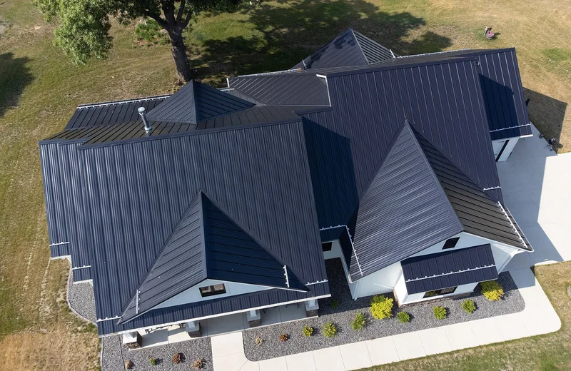 Aerial view of a house with a dark standing-seam metal roof